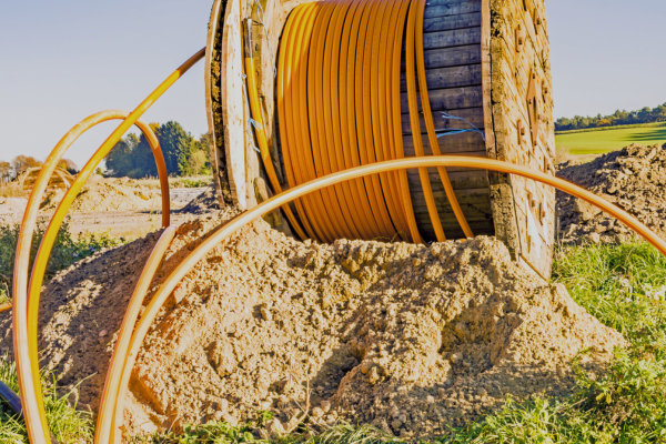 Image of orange fiber cables in piles of dirt.