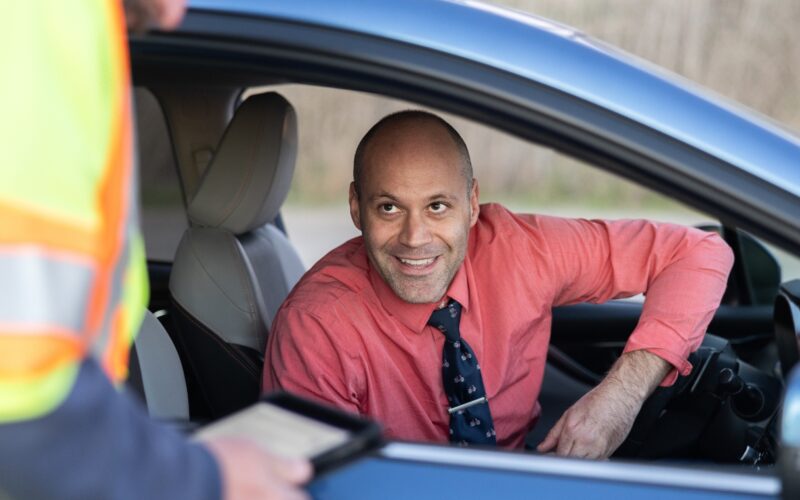 Freeway Service Patrol agent helping a customer in their vehicle - customer has a blue tie and salmon-color shirt