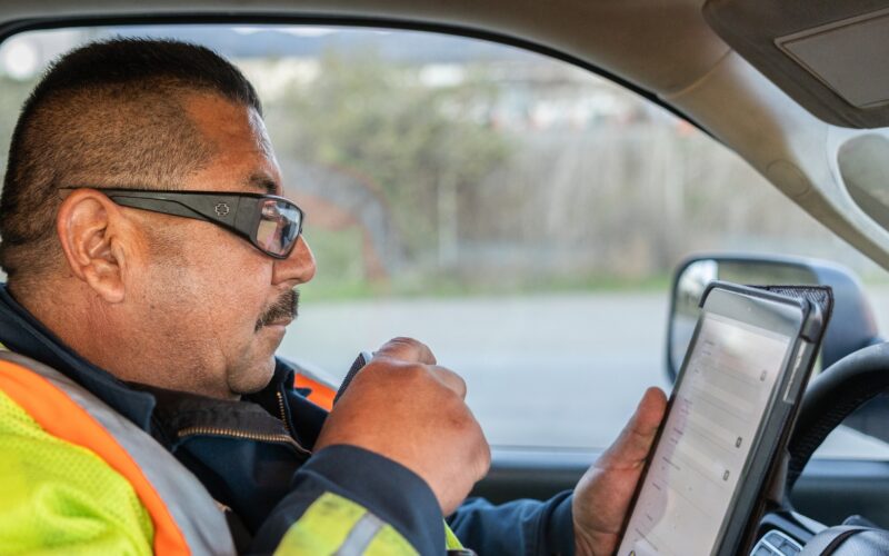 Freeway service patrol agent calling in an incident on his radio with iPad showing scene details